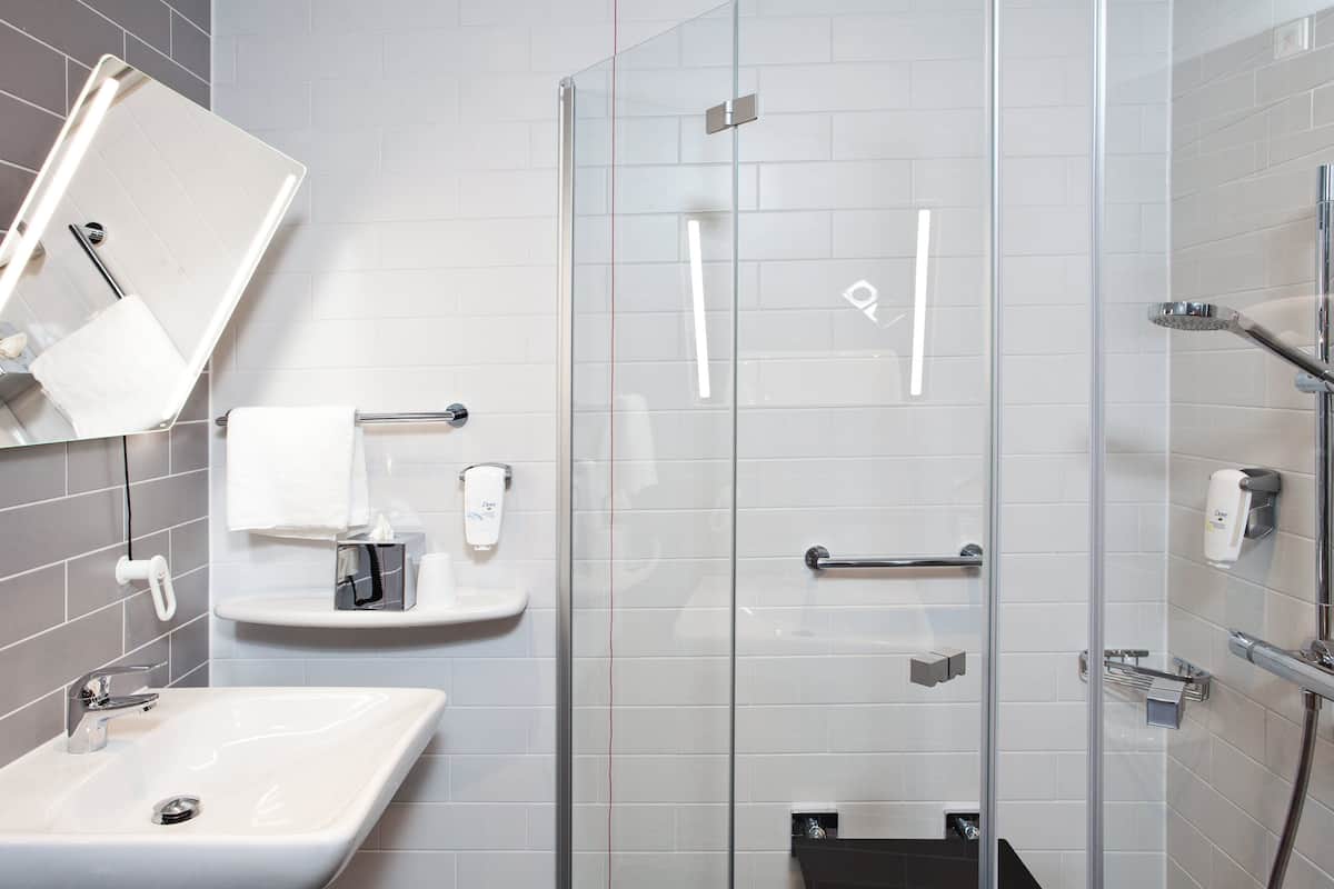 Une salle de bain moderne avec une douche à parois de verre, un lavabo et un miroir.
