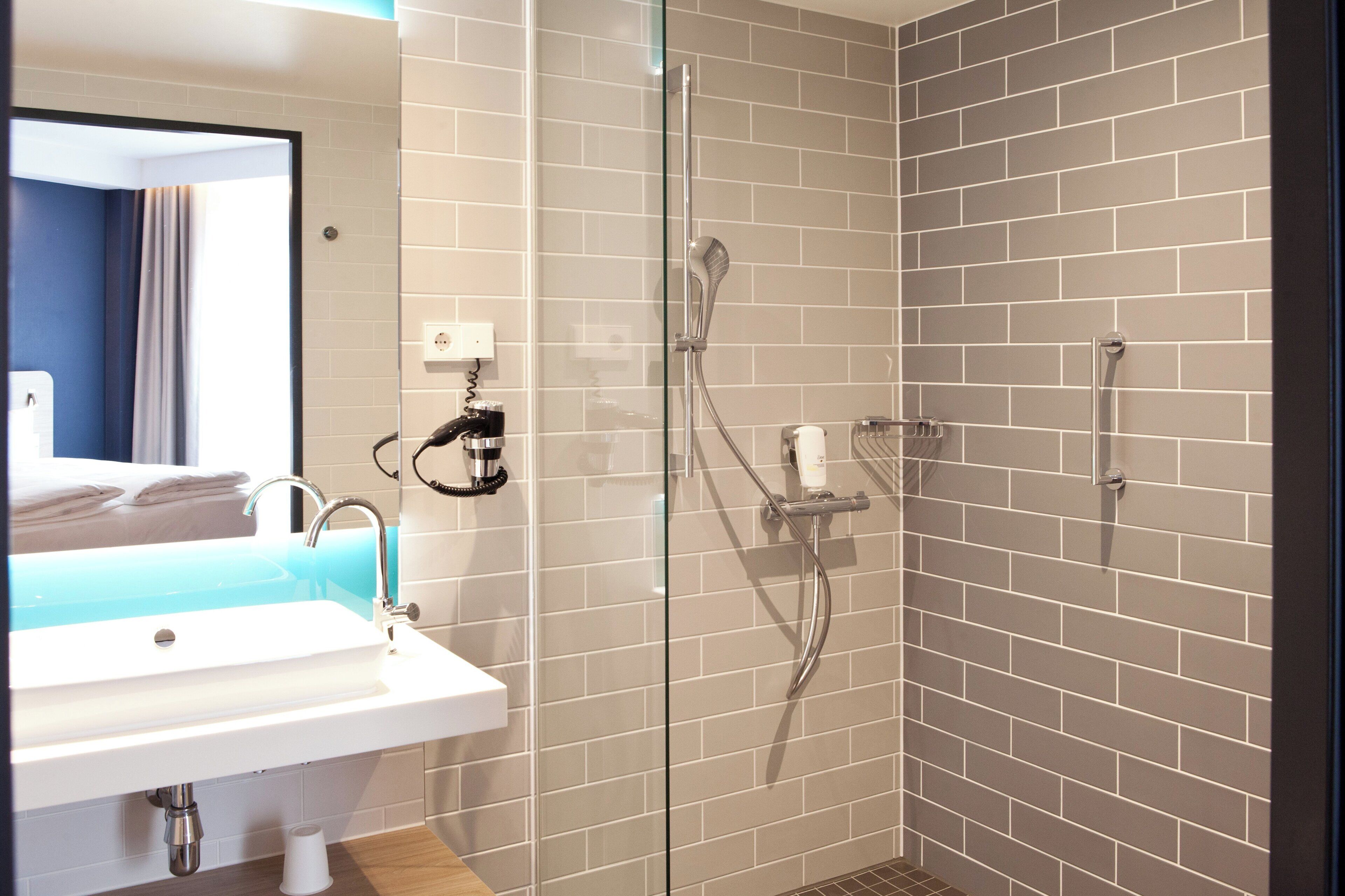 A modern bathroom with a sink, mirror, and shower.