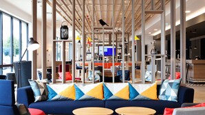 A modern interior with a blue sofa, wooden tables, and a variety of colorful pillows. - Holiday Inn Express Offenburg by IHG (Offenburg)