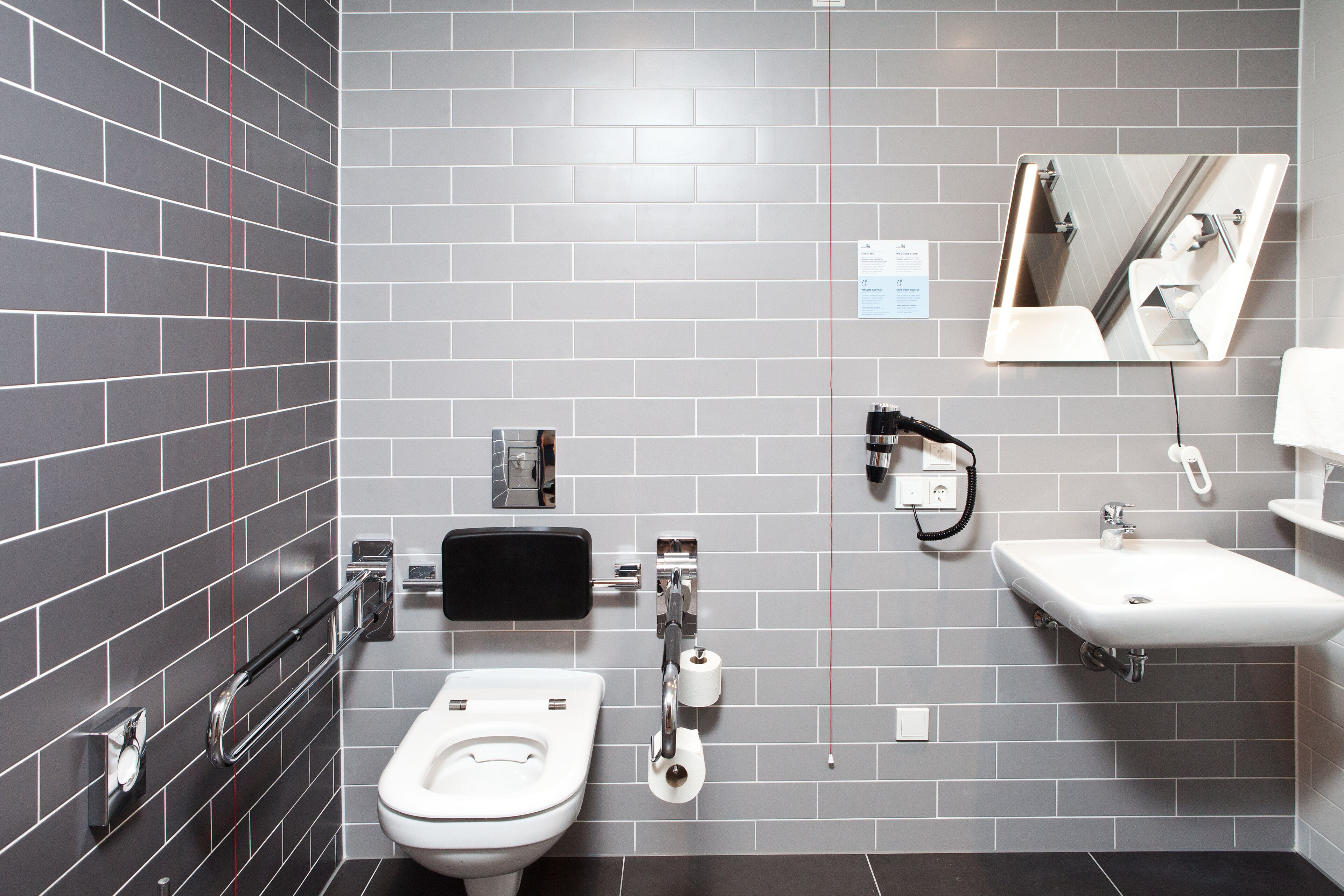 A modern bathroom with a toilet, bidet, sink, and mirror.