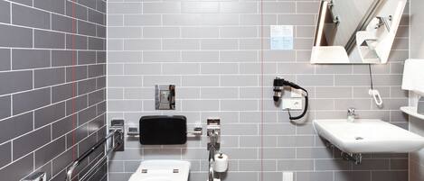 A modern bathroom with a toilet, bidet, sink, and mirror.