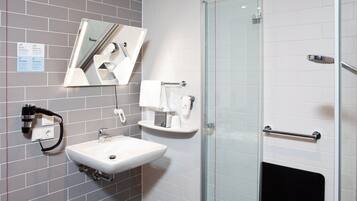 A modern bathroom with a glass shower enclosure, a white sink with a mirror above it, and a towel rack.