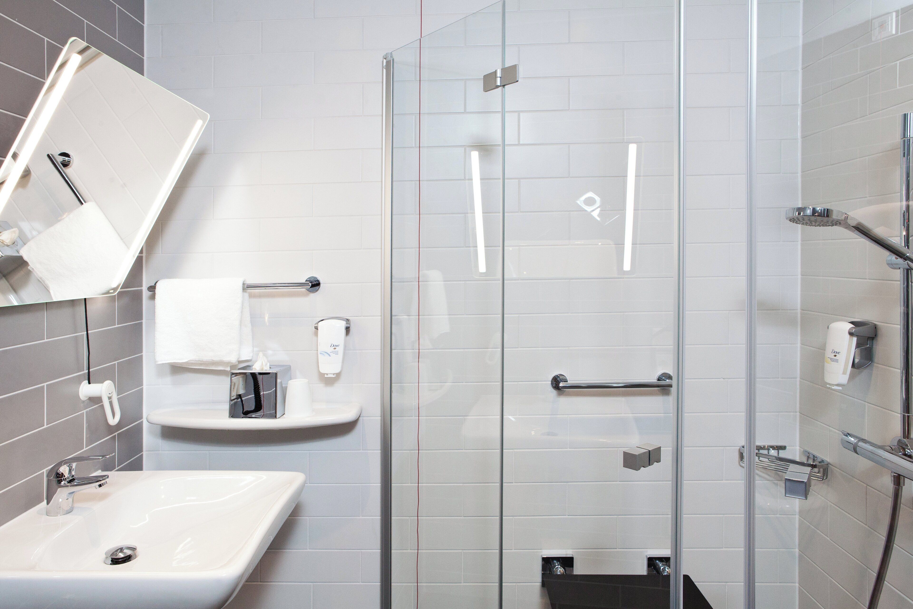 A modern bathroom with a glass shower enclosure, a sink, and a towel rack.