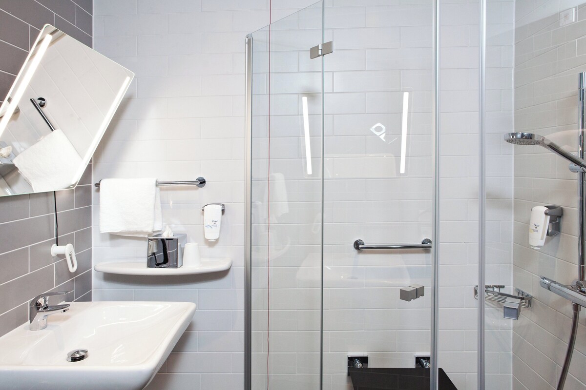 A modern bathroom with a glass shower enclosure, a sink, and a mirror.