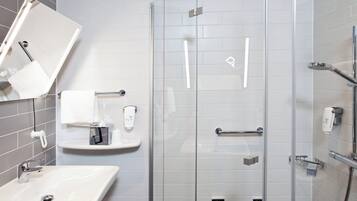 A modern bathroom with a glass shower enclosure, a sink, and a towel rack.