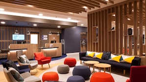 A modern hotel lobby with a reception desk, seating area, and a wooden partition. - Holiday Inn Express Offenburg by IHG (Offenburg)