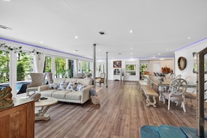 Un salon spacieux comprenant un canapé, des fauteuils, une table à manger et donnant sur l’extérieur.