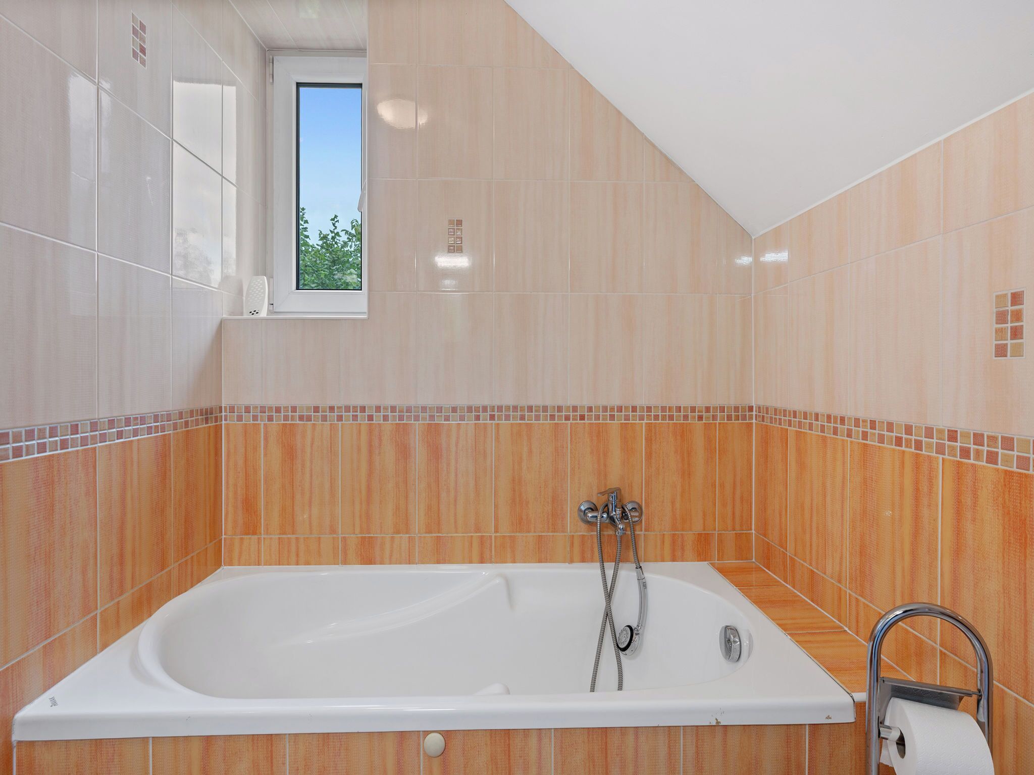 Un baño moderno con una bañera grande, una ventana y una ducha.