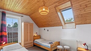 Een slaapkamer met een schuine kap, dakraam, een bed, een kledingkast, een nachtkastje en een radiator.
