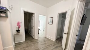 A hallway with wooden flooring, white walls, and open doors leading to other rooms. - Modern Beachfront Suite 206 (Ocean City)