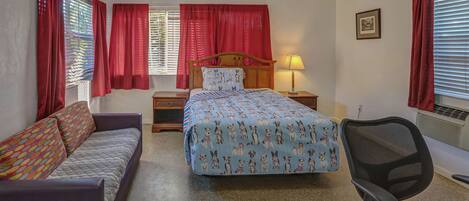 Une chambre à coucher comprenant un lit, un bureau, une chaise, un canapé et une table de chevet.