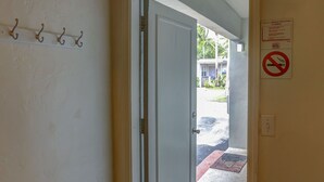 Ein Hotel Eingang mit Tür, Fußmatte, einem Rauchverbot-Schild und einem Wandhaken.