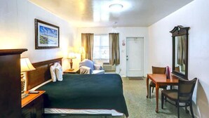 Ein Hotelzimmer mit Bett, Nachttisch, Lampe, Stuhl und Spiegel.