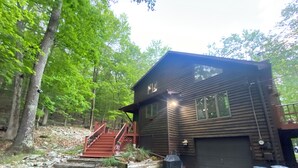 A wooden cabin with a covered porch, a garage, and a stone staircase leading up to the entrance. - Eagle Rock Resort 1 Block from the Lake ONLY EAGLE ROCK MEMBERS MAY RENT (Hazleton)