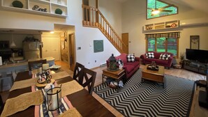 A spacious living area with a staircase, a dining table set with placemats, and a television in the corner. - Eagle Rock Resort 1 Block from the Lake ONLY EAGLE ROCK MEMBERS MAY RENT (Hazleton)