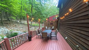 A wooden deck with a table and chairs, surrounded by a railing and string lights. - Eagle Rock Resort 1 Block from the Lake ONLY EAGLE ROCK MEMBERS MAY RENT (Hazleton)