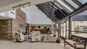 A spacious indoor area with a high ceiling, a chandelier, and a seating area with a bench and two sofas. - Ocean view, 2BR, 2BA Condo, St. Regis #3213, Topsail, NC (North Topsail Beach)