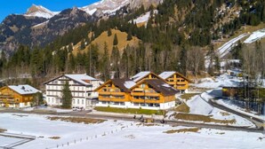 A mountain lodge with multiple wooden buildings, a ski slope, and snow-covered terrain.