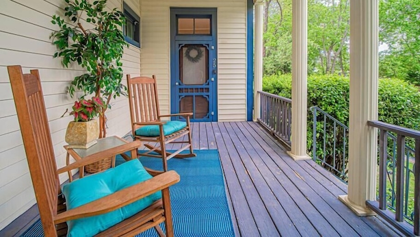 A porch with wooden chairs and a potted plant.