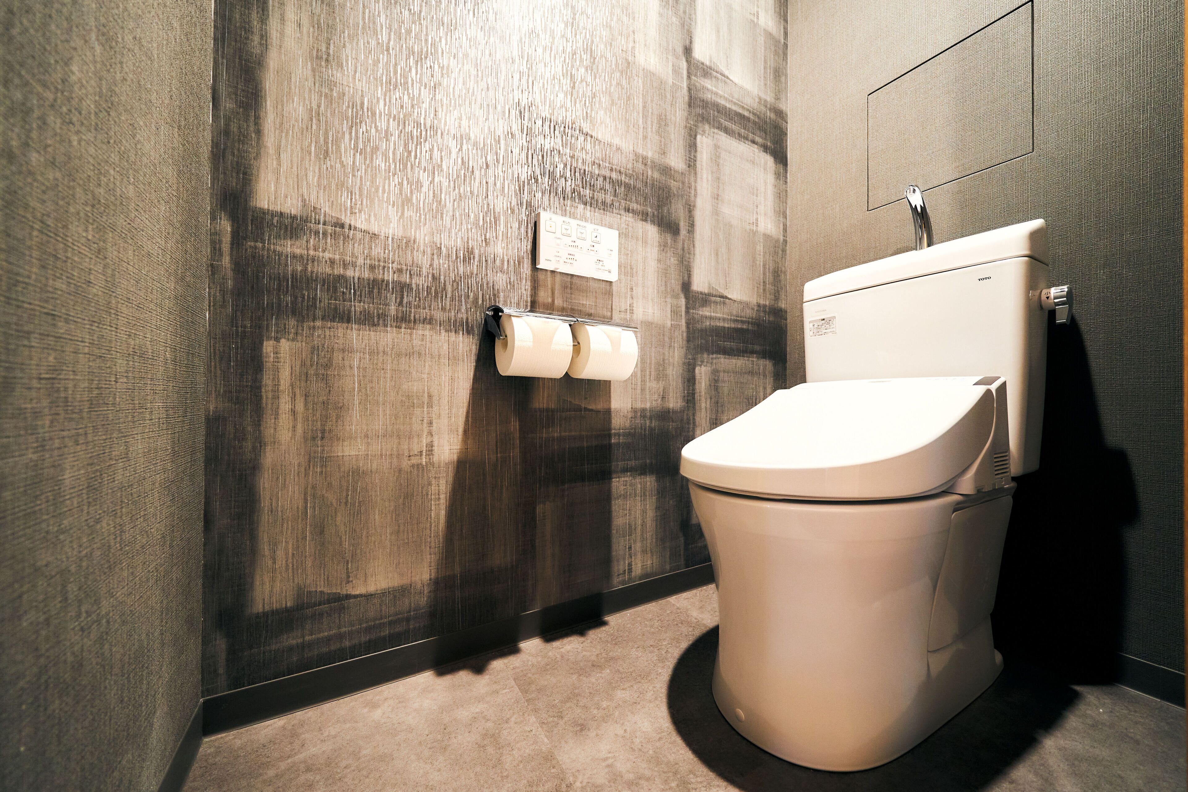 A modern bathroom with a toilet, a towel dispenser, and a wall-mounted sign.
