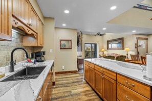 A kitchen with wooden cabinets, a marble countertop, and a ceiling fan.