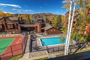 Zona residencial con piscina, canchas de tenis y vistas a las montañas.