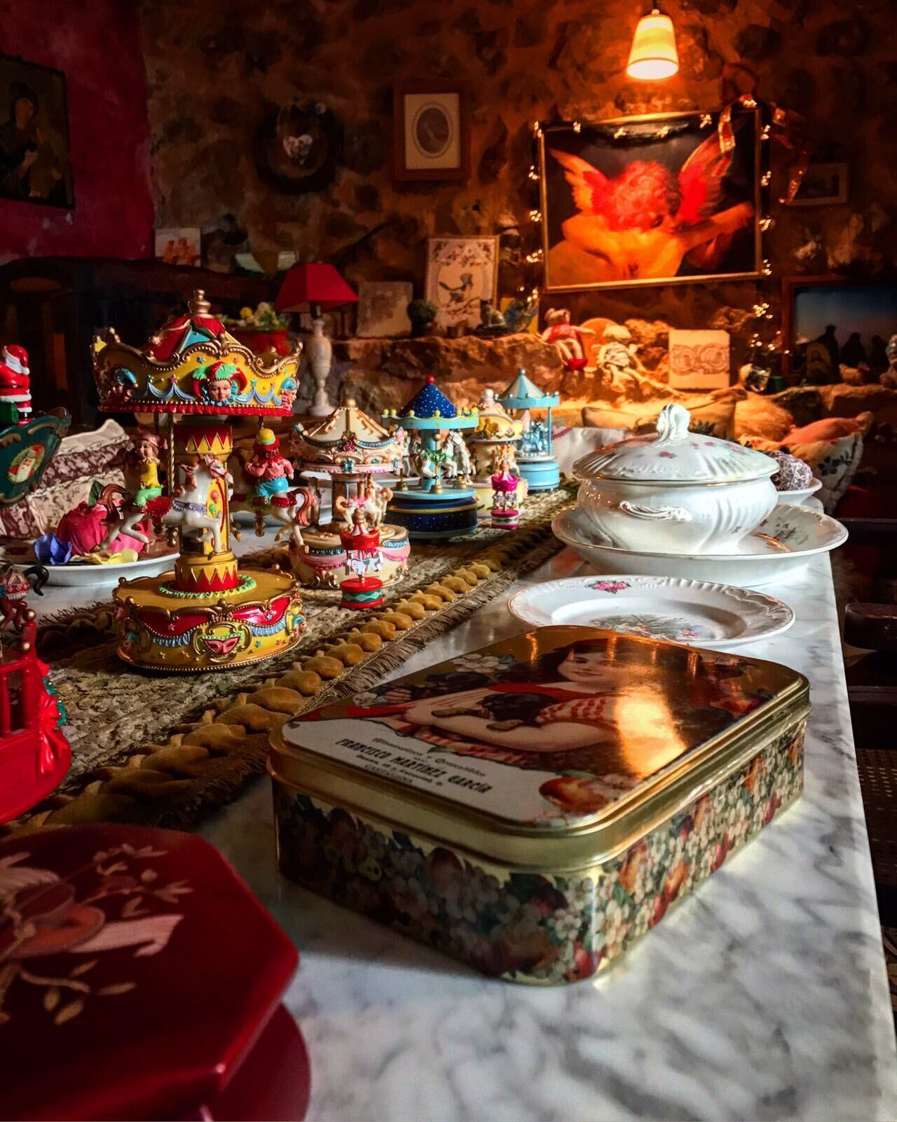 Een eettafel met diverse decoratieve objecten, waaronder een draaimolen, beeldjes en een grote blikken doos.