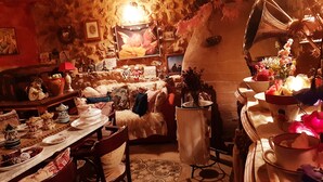 A cozy room with a rustic stone wall, a dining table set with plates and a chandelier, and a large mirror reflecting the room. - Romantic getaway to Valeria (Valeria)