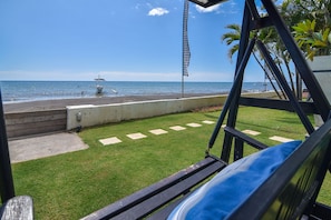 Enjoy a serene beachfront view from this balcony, featuring a fountain in the distance and a comfortable seating area.
