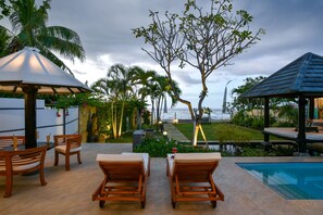 A poolside area with lounge chairs, a small table, and a statue.