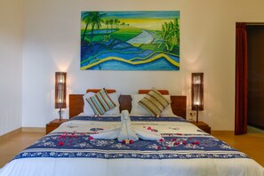 A hotel room with a large bed, two bedside lamps, and a painting of a landscape on the wall.