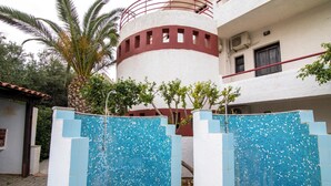 A building with a white exterior, a red balcony, and a tiled pool area. - Irilena Apartments (Hersonissos)