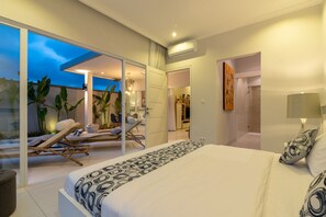 Une chambre moderne avec un grand lit, un balcon doté de fauteuils de relaxation et une vue sur le ciel.