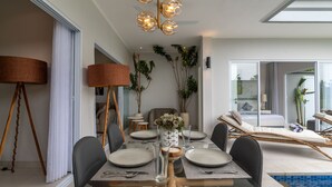 A modern dining area with a glass table, black chairs, and a central vase. - Villa Shiva (Sukasada)