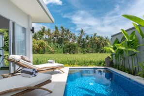 A modern outdoor pool area with lounge chairs, a clear blue pool, and lush greenery in the background. - Villa Shiva (Sukasada)