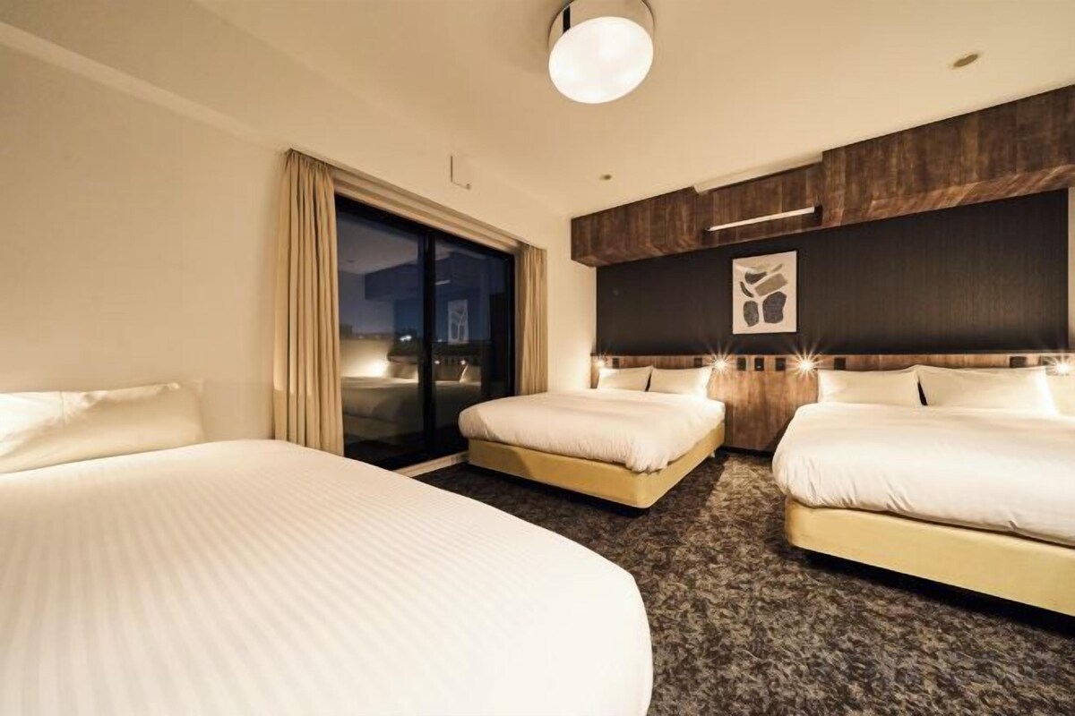 Ett hotellrum med två sängar, en skjutdörr som leder ut till en balkong och en mörk trägavel.