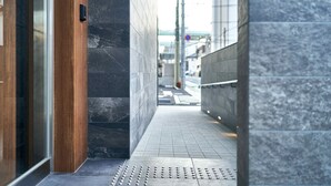 A modern building entrance with a wooden door, dark stone walls, and a metal handrail. - Grand STAY Hakata Station North (Fukuoka)