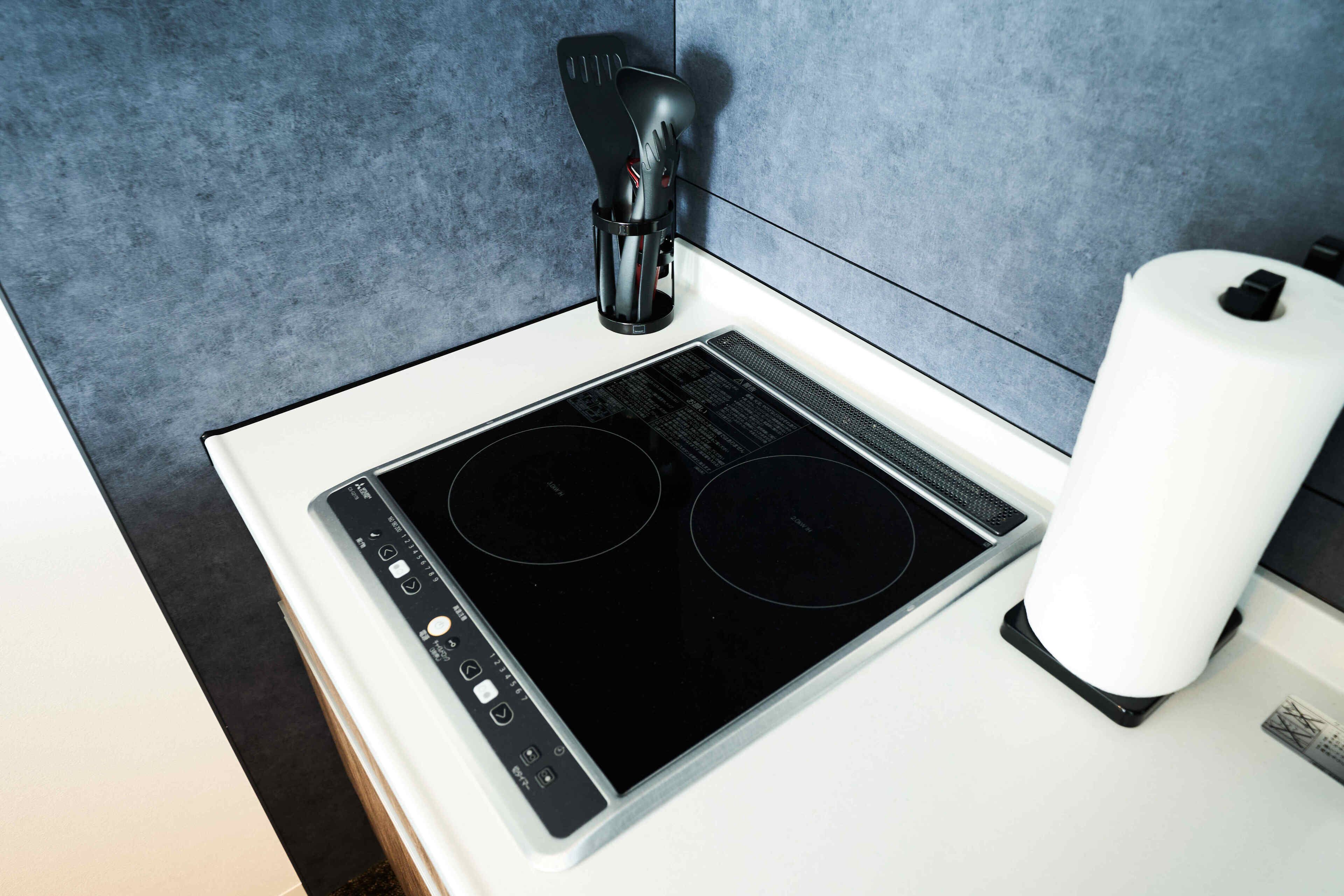 A kitchen with a black induction cooktop and a white countertop.