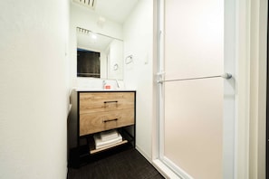 A small bathroom with a wooden vanity, a mirror, and a towel shelf. - Grand STAY Hakata Station North (Fukuoka)