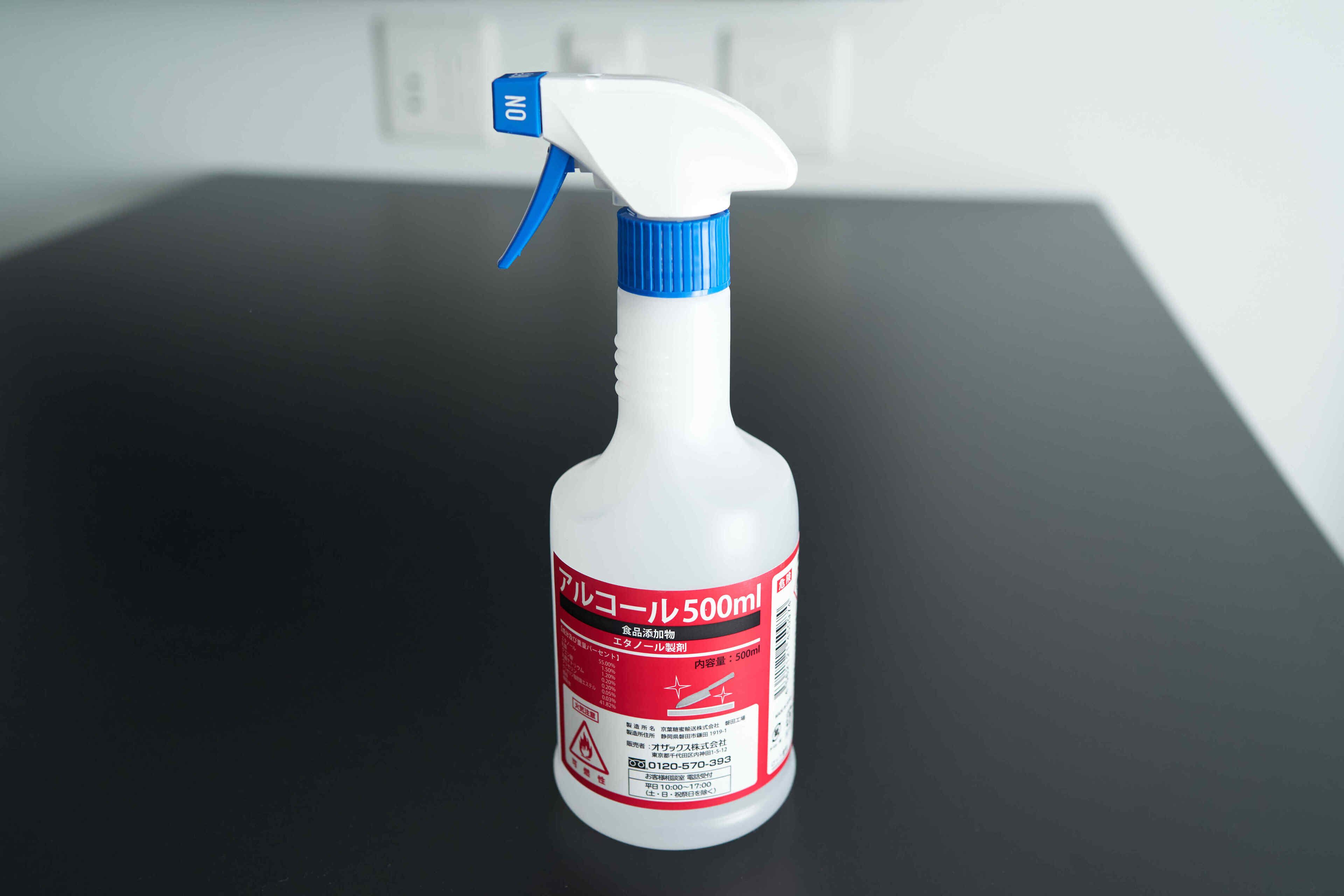 A white spray bottle with a blue nozzle and a red label.