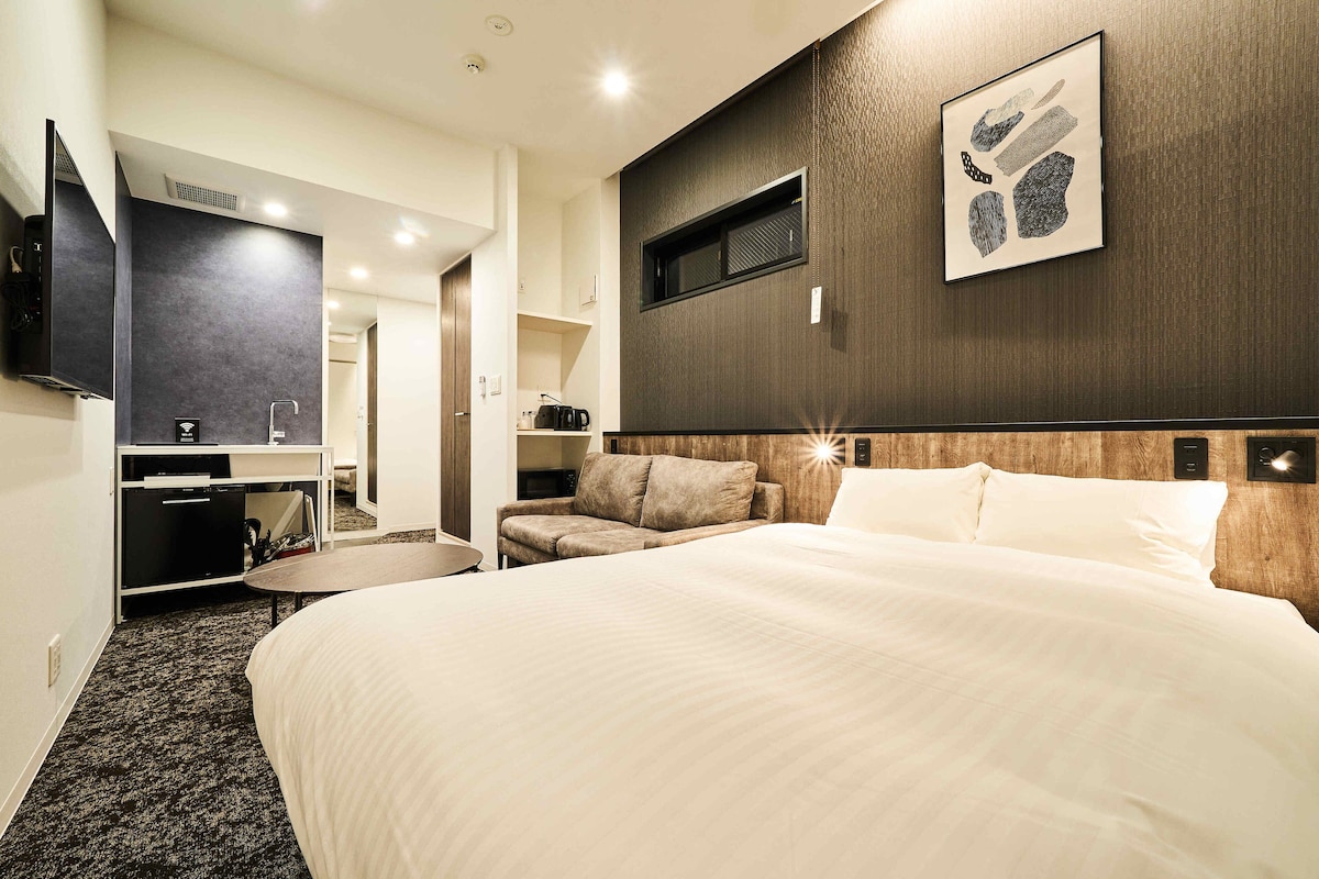 Una habitación de hotel moderna con una cama grande, un sofá, un escritorio y un televisor.