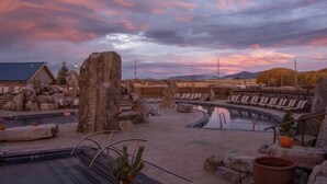 Une zone de sources chaudes avec de gros rochers, une piscine et des chaises longues.