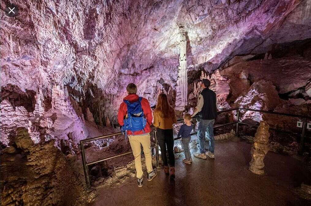 A group of people inside a cave with stalactites and stalagmites.
