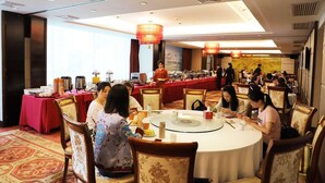 A dining area with round tables, chairs, and a buffet setup. - Yijian Haoting Holiday Hotel (Zhuhai)