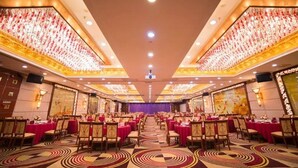 A banquet hall with round tables, chairs, and a stage at the front. - Yijian Haoting Holiday Hotel (Zhuhai)