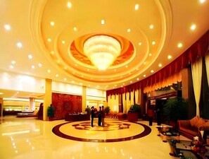 A hotel lobby with a central circular design, a reception desk, and seating areas.