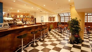 A bar area with a checkered floor, bar stools, and a variety of bottles and glasses. - Cordon (Burgos)