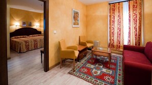 A hotel room with a bed, two armchairs, a coffee table, and a red sofa. - Cordon (Burgos)