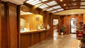 A hotel reception area with a wooden reception desk, a clock, and a potted plant. - Cordon (Burgos)
