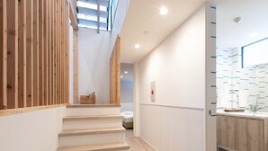 Interior moderno de hotel con una escalera de madera, un baño con pared estampada y un techo con tragaluces.